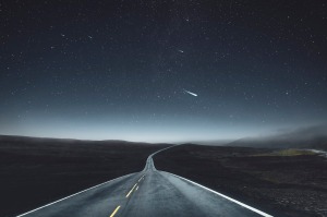 En la imagen se ve una carretera que se prolonga hasta el horizonte. Es de noche, una noche estrellada, y sobre el cielo se puede ver el rastro de un cometa luminoso.